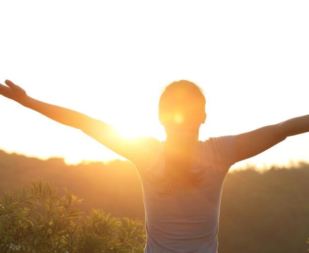 a lady with arms open , sunrising depicting emotional healing