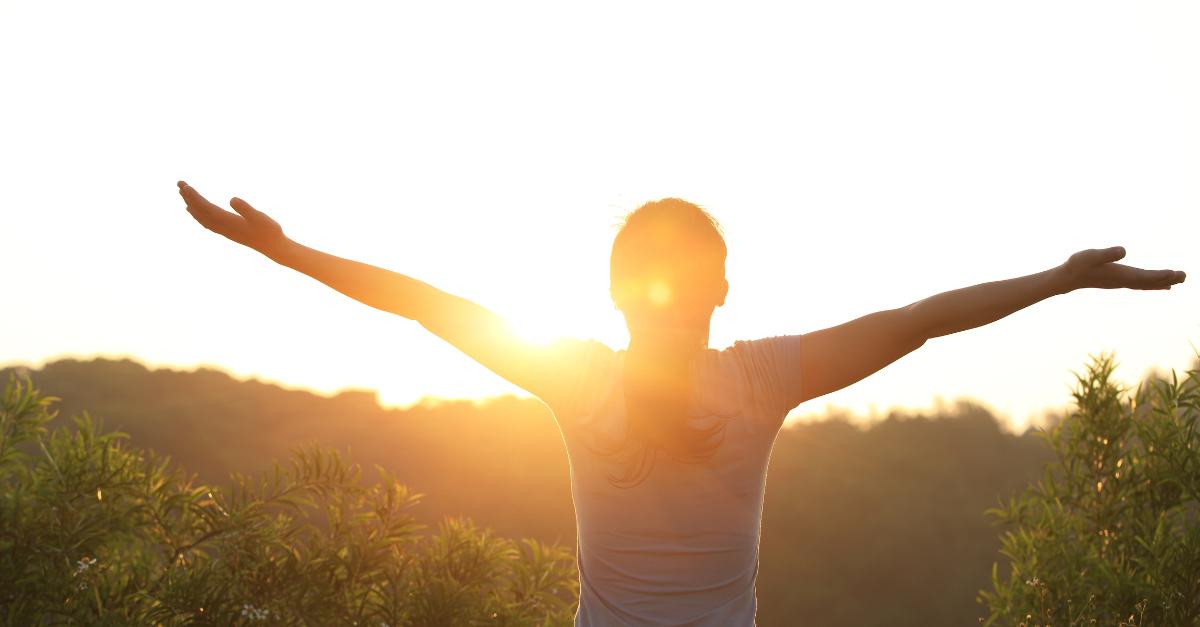 a lady with arms open , sunrising depicting emotional healing