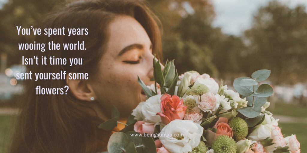 woman holding and smelling a bouquet of flowers with a message about self-love.